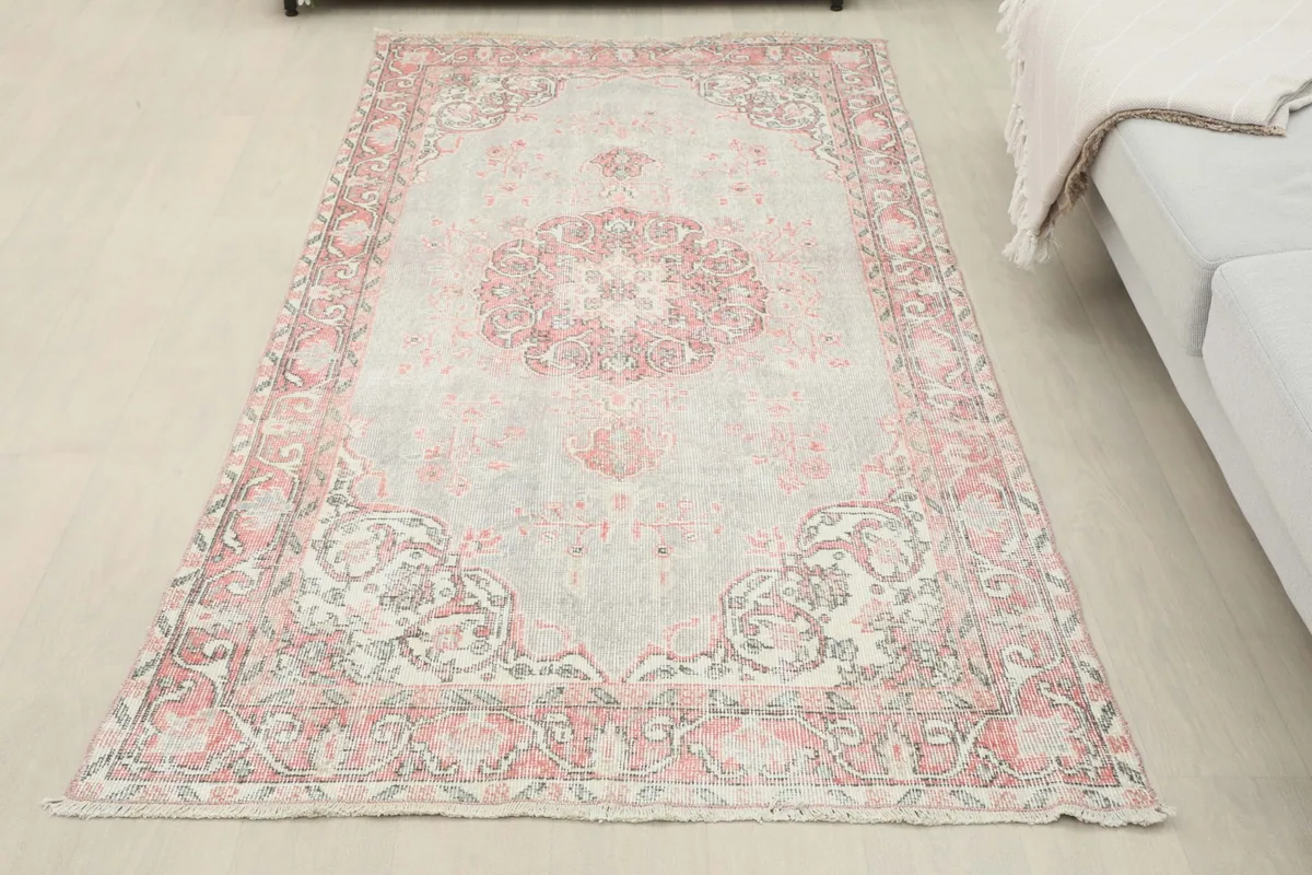 Full view of the gray and rose vintage rug laid out in a room, showing its overall presence.