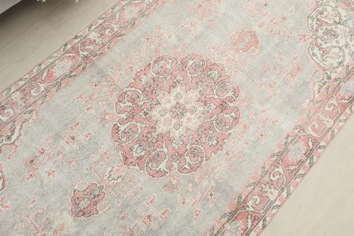 Detailed view of the central rose medallion and surrounding gray field of the rug.
