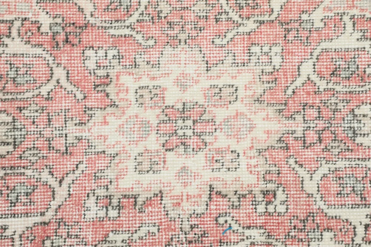Close-up of the hand-knotted wool pile, showing the rose and ivory color variations.