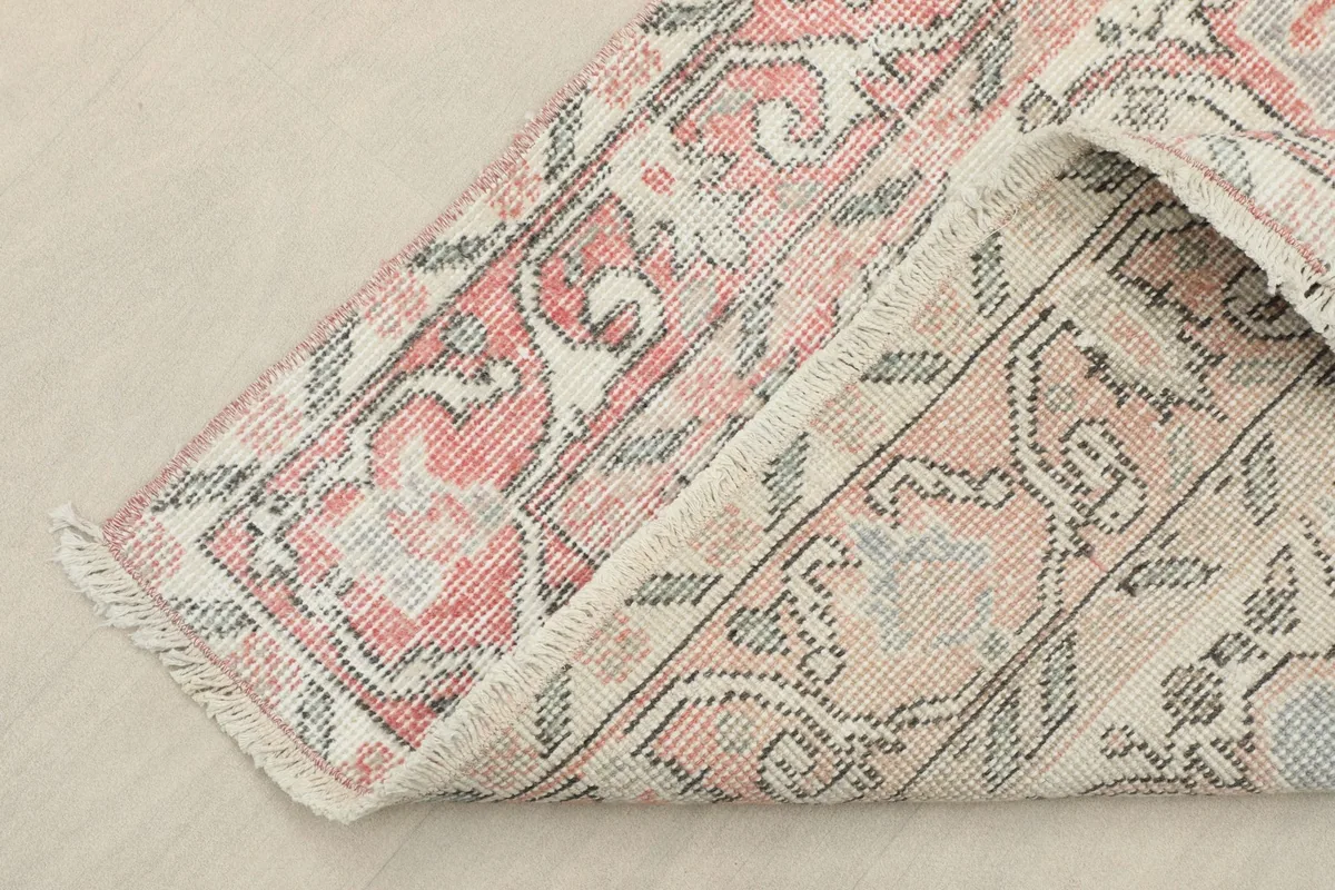 View of the rug's edge, revealing the hand-knotted cotton foundation and short fringes.