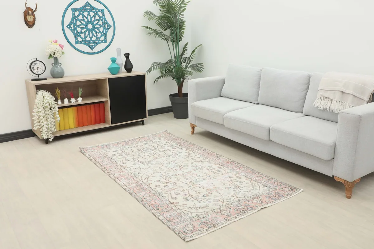 Ivory and rose floral vintage rug displayed in a living room setting with a light gray sofa and modern decor.