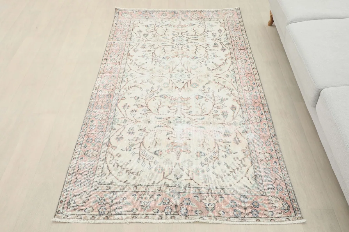 Overhead view of the ivory and rose floral rug placed in a living space next to a sofa.