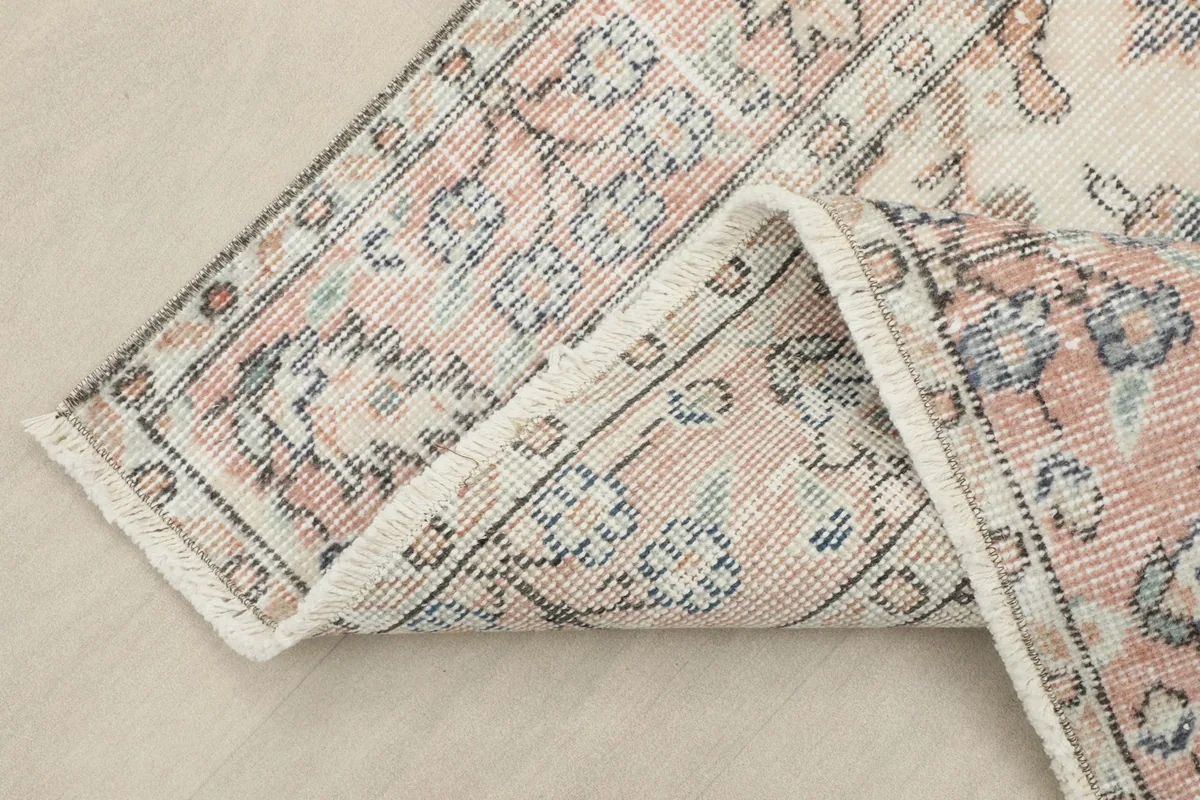 Close-up of the rose border and fringe, showing the texture and the vintage patina of the rug.