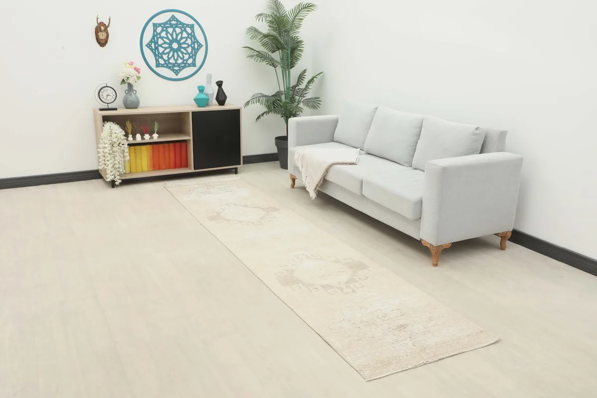 Runner rug in a modern living space next to a light gray sofa, showcasing its length and subtle pattern.