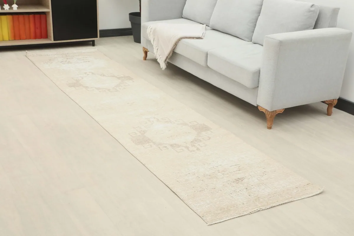 Angled view of the ivory runner rug in a room, highlighting its neutral tones and faded geometric designs.
