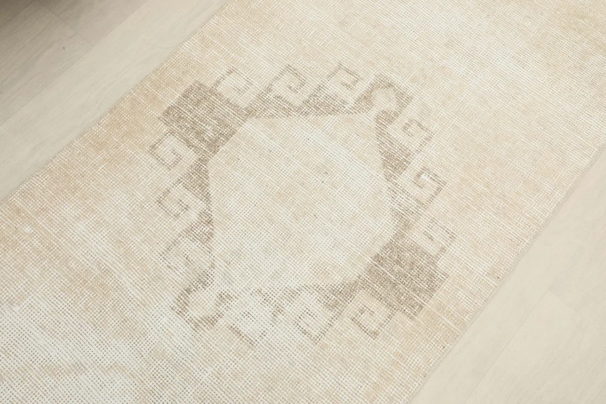 Close-up on one of the central geometric medallion motifs in muted beige and gray tones.