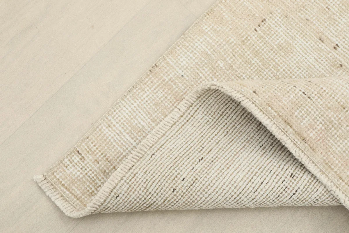 Corner of the rug folded to reveal the hand-knotted cotton foundation on the reverse side.