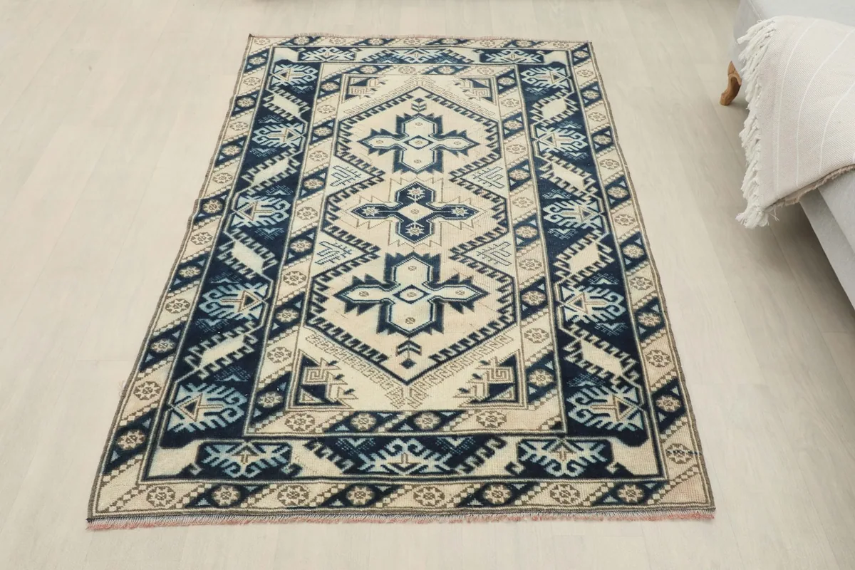 Another room view of the rug, laid out flat on a light floor, enhancing its ivory and navy colors