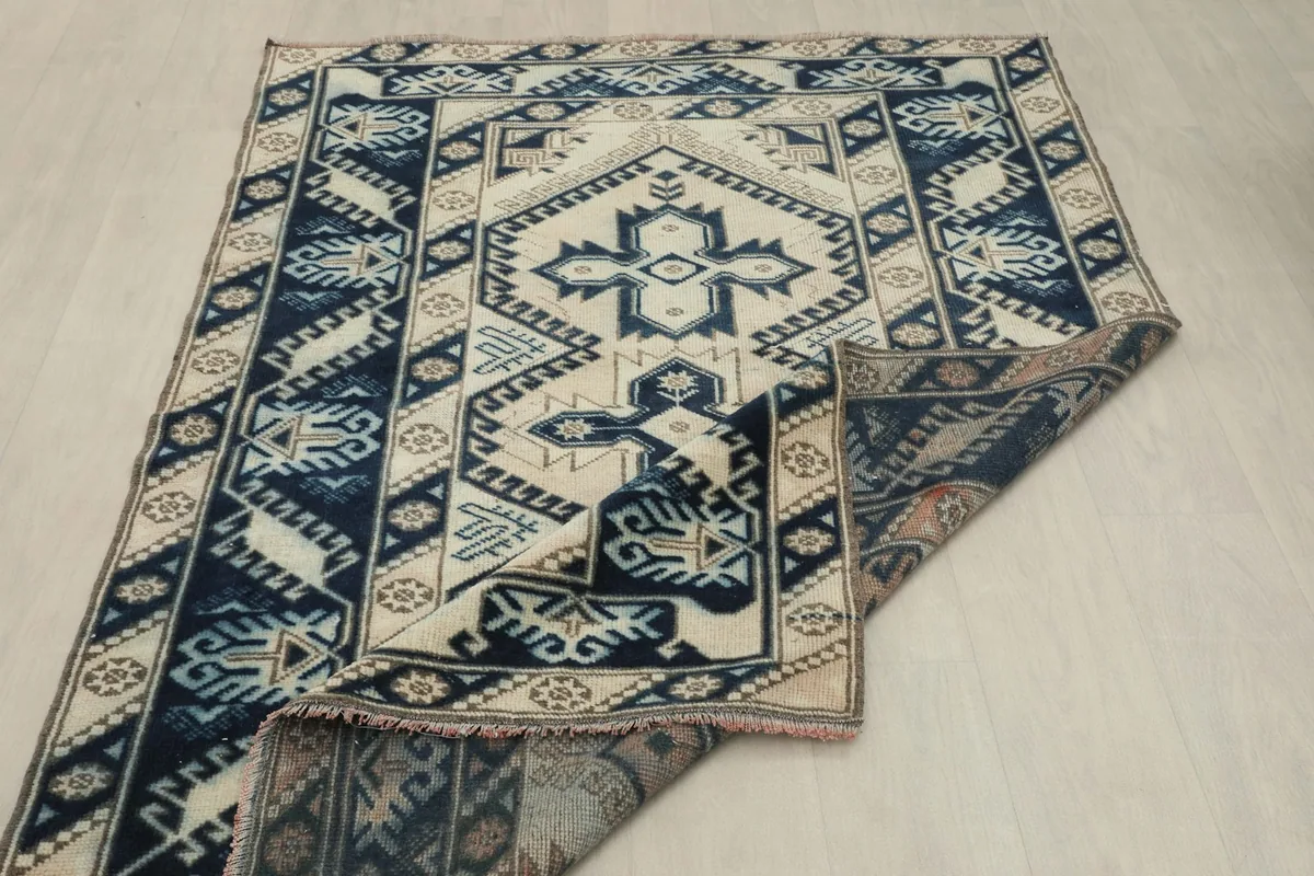 Rug partially folded to show the thickness and flexibility of the vintage wool pile