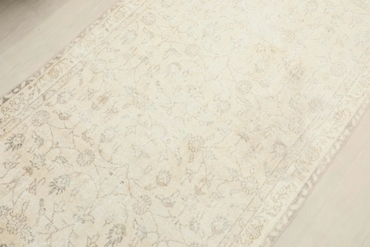Diagonal view across the rug, emphasizing the overall soft ivory and beige coloration