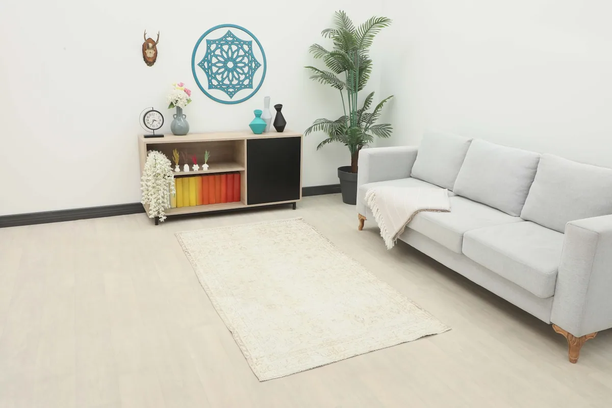 Ivory vintage rug placed in a modern living room setting with a sofa and cabinet