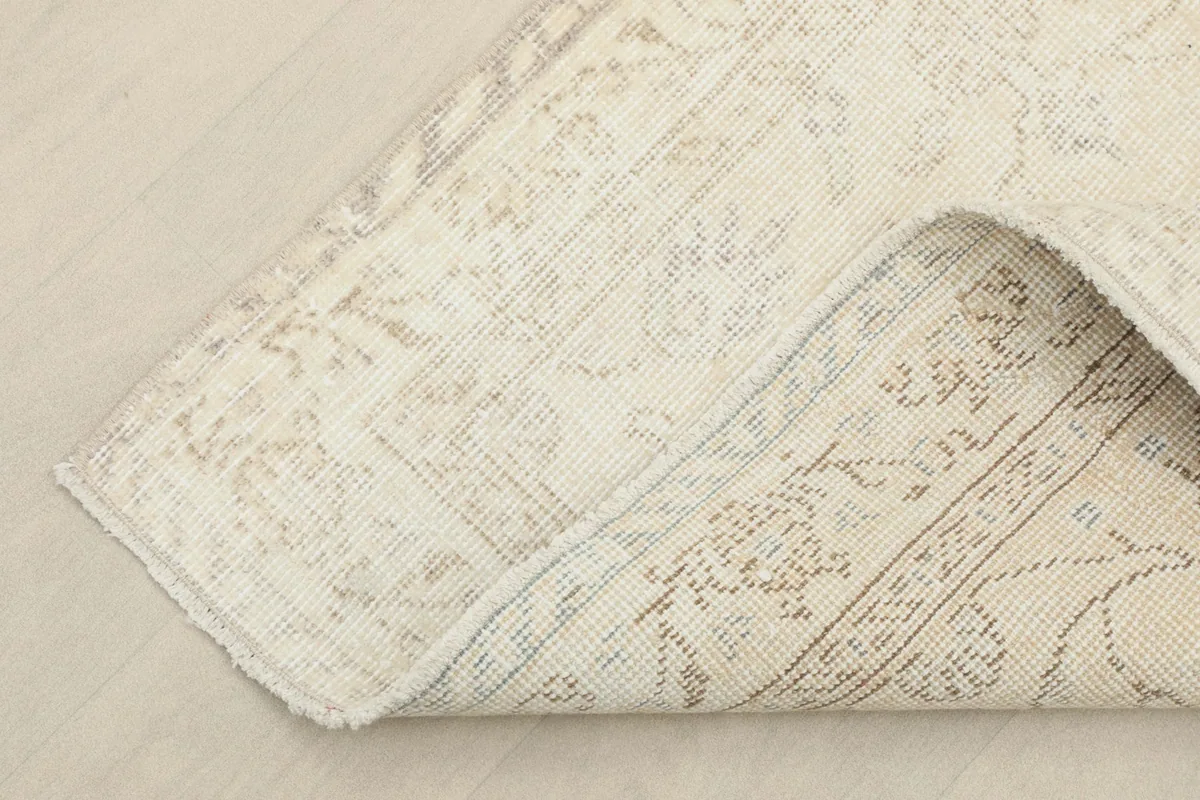 Corner of the rug folded back, revealing the cotton foundation and reverse side of the knots