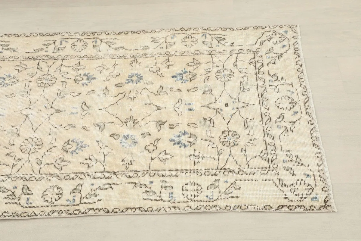 Close-up of the runner's end, showing the cream field and blue floral-geometric border patterns.