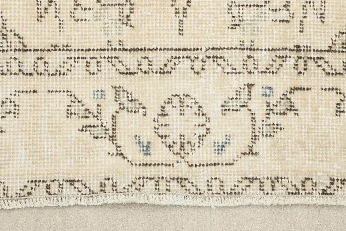 Detail of the rug's end, showcasing the natural cotton foundation and the short, simple fringe.