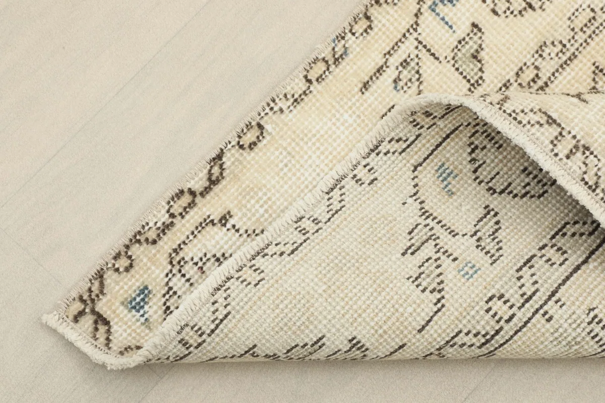 Corner of the runner folded back, revealing the cotton foundation and the reverse side of the knots.
