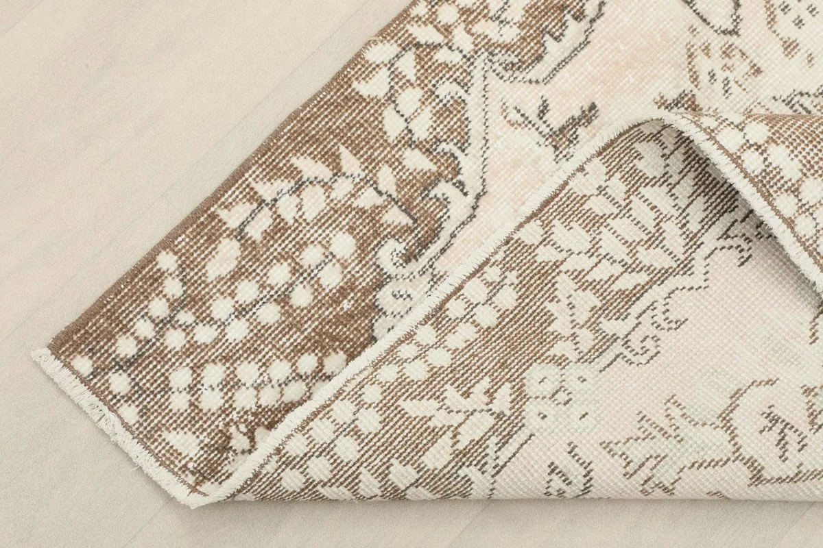 Corner of the rug folded back, revealing the cotton foundation and reverse side