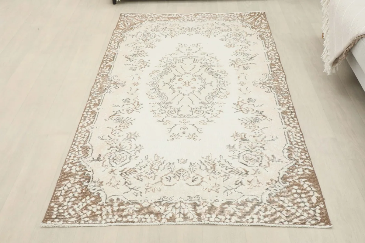 Full overhead view of the ivory and tan floral vintage rug in a room