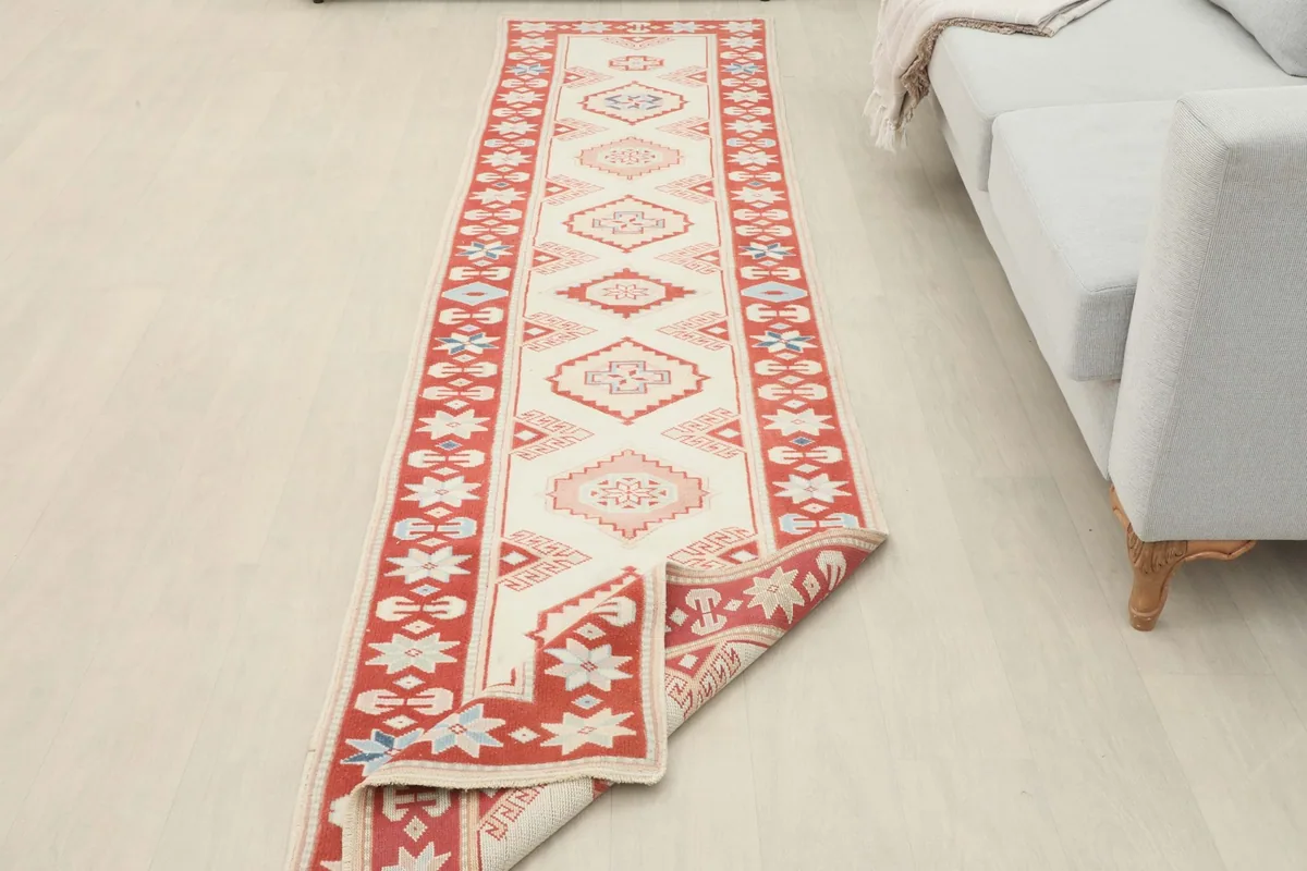 Long view of the runner rug laid out in a room next to a sofa, showing its full length