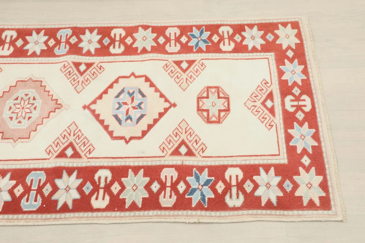 Close-up of the rug's geometric motifs and the red border with star designs