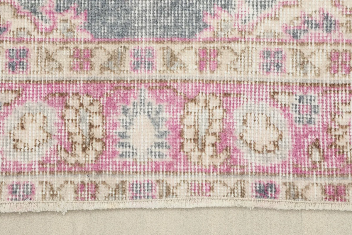 Close-up detail of the pink, beige, and gray border patterns on the rug