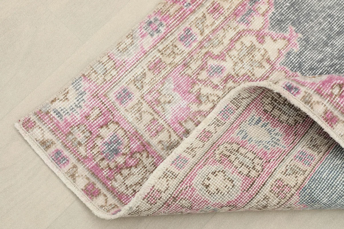 Corner of the rug folded back, showing the wool pile and cotton foundation