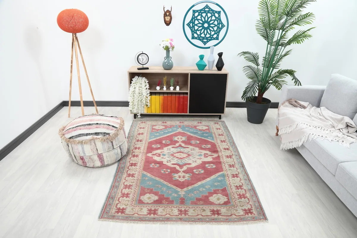 Vintage red and blue geometric rug placed in a living room setup with a light gray sofa and modern decor.