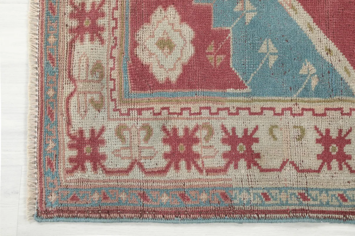 Corner detail of the rug, illustrating the intricate tribal patterns within the beige and blue border.