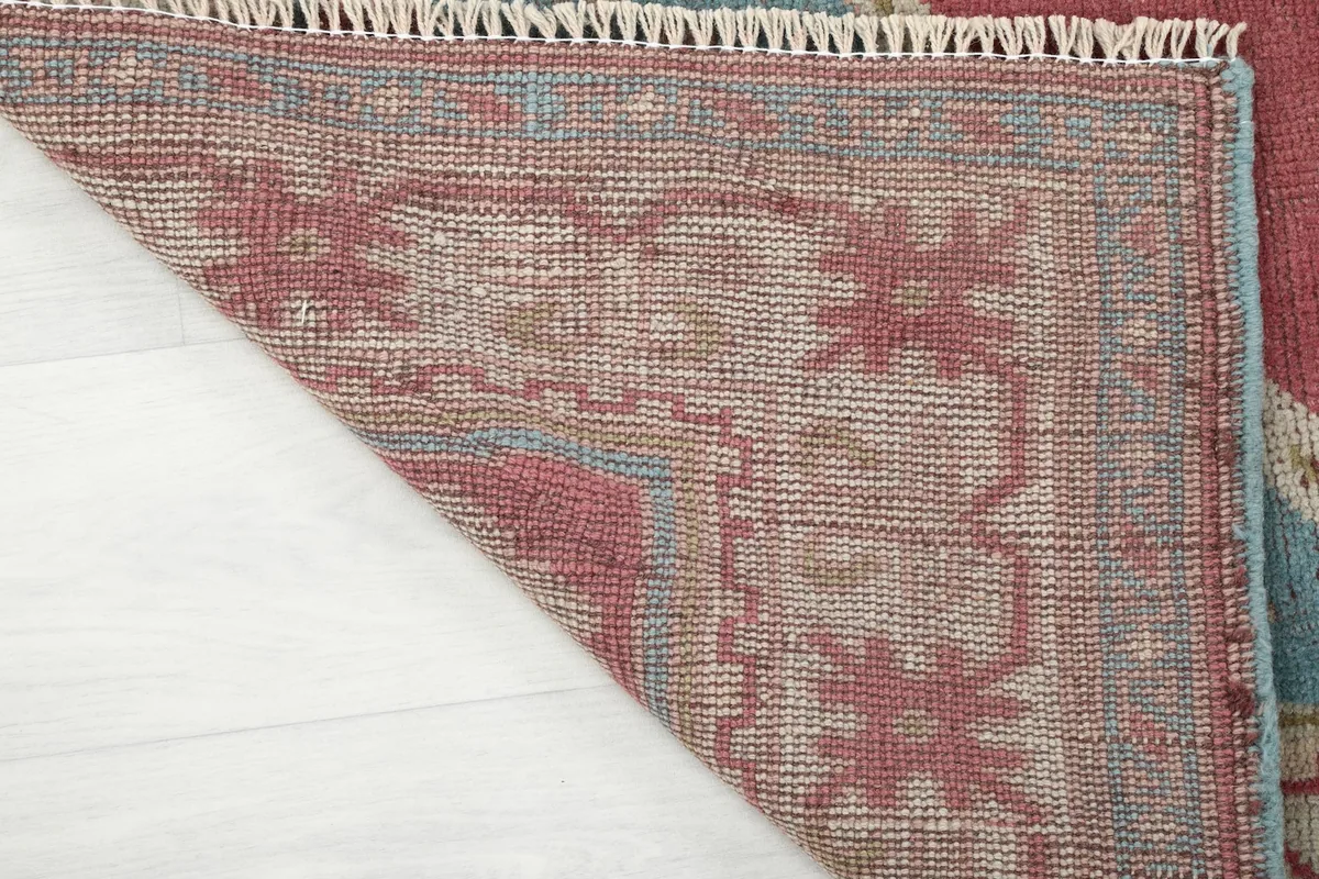 Close-up of the rug's backside, showing the tight knotting of the wool pile on its cotton foundation.