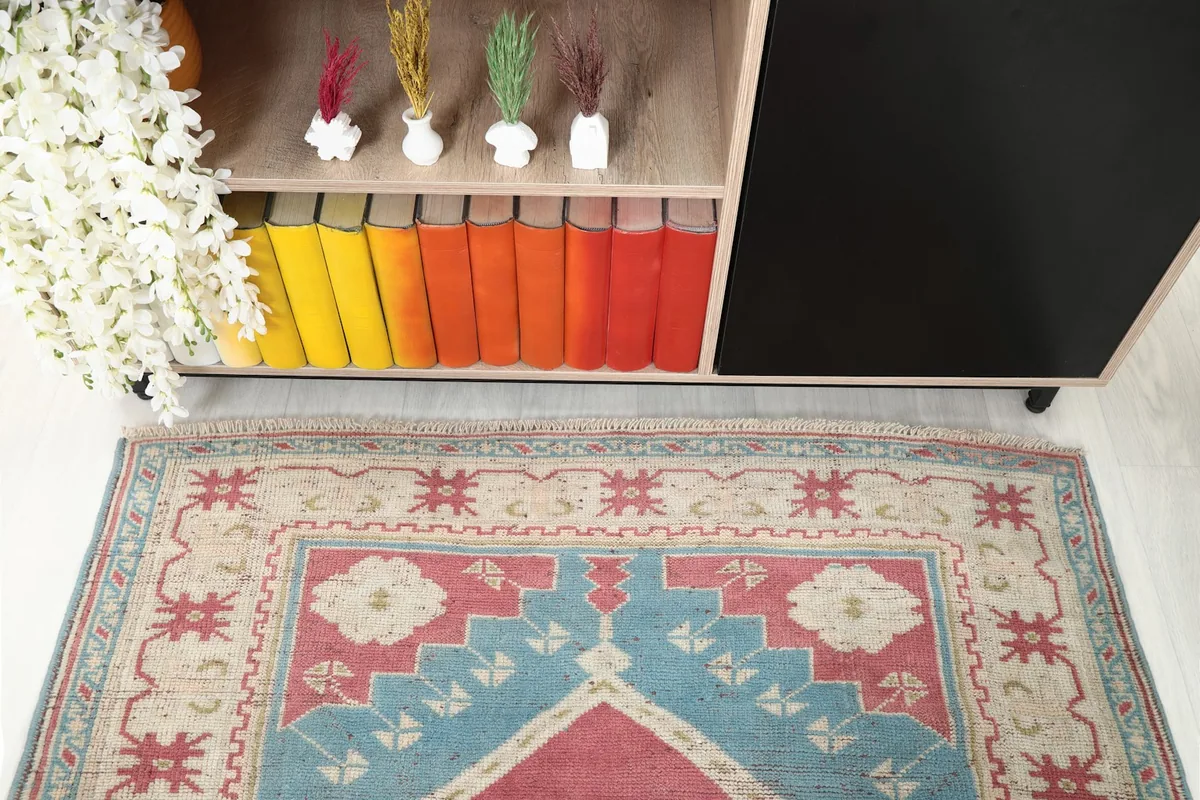 Overhead detail shot of the rug's upper section and border, next to a cabinet with colorful books.