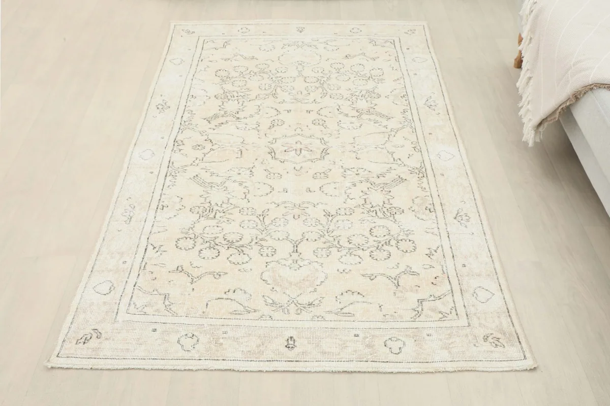 Full view of the beige floral rug laid out in a room, seen from a higher angle