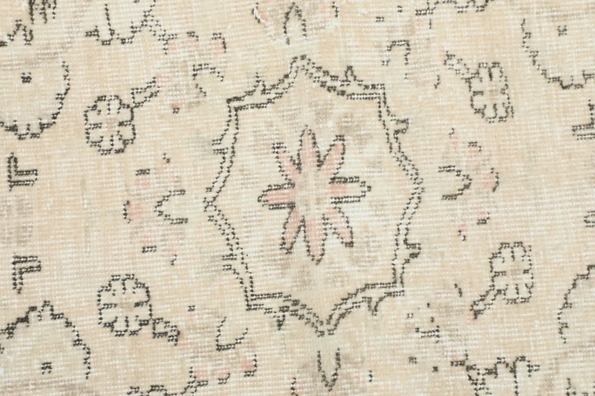 Detailed close-up of the central medallion motif with a subtle rose accent in the beige rug