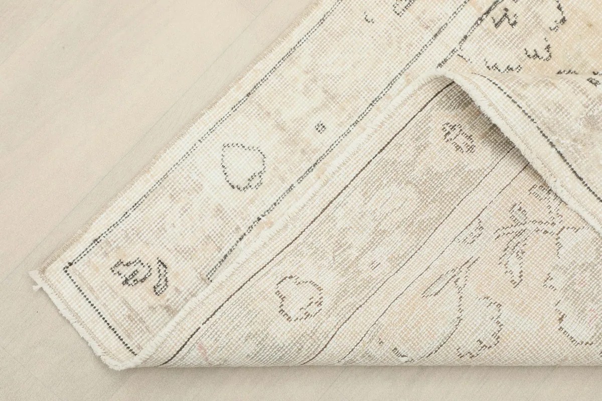 View of the rug's underside and folded corner, revealing the cotton foundation and knotting