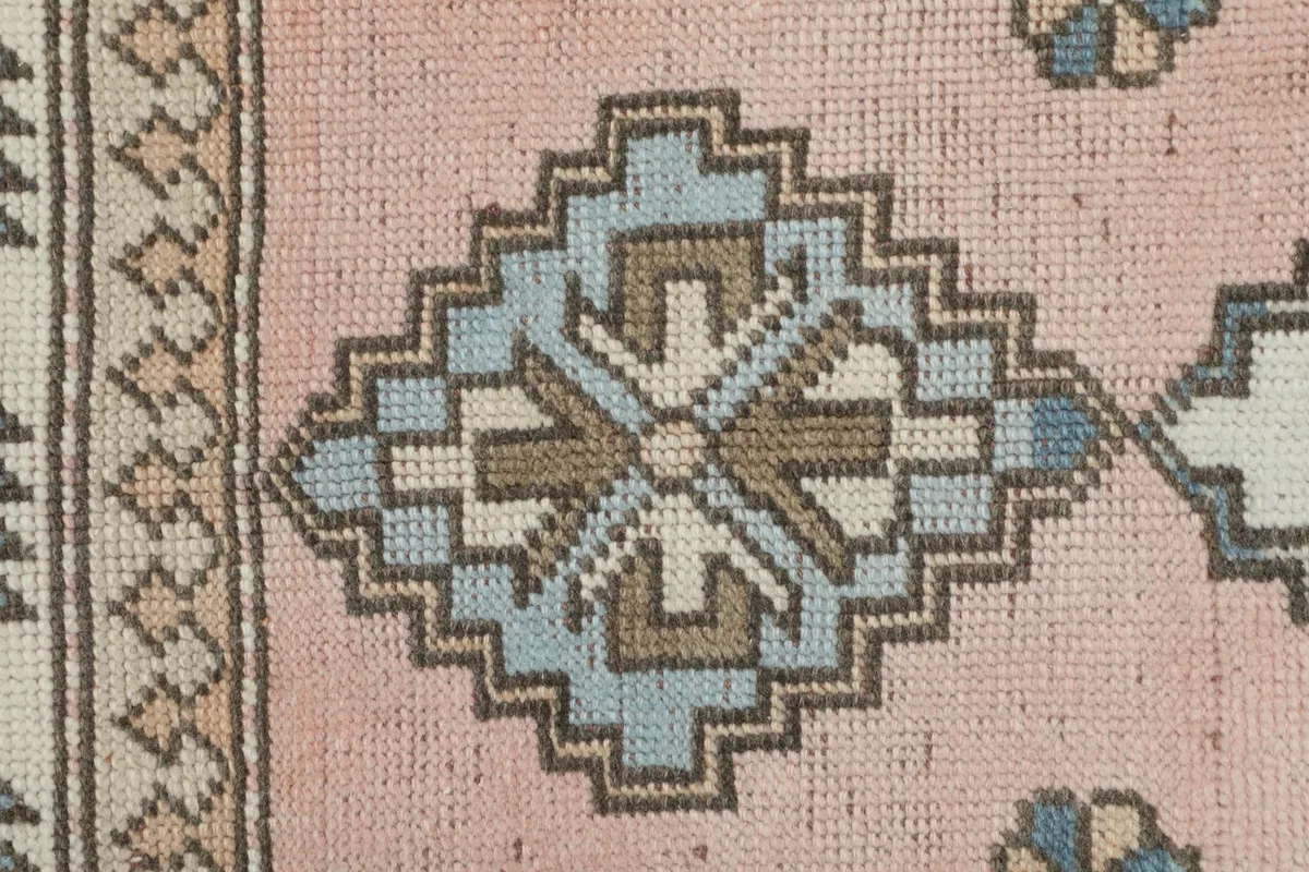 Detailed close-up of a blue and beige geometric medallion on the rose field
