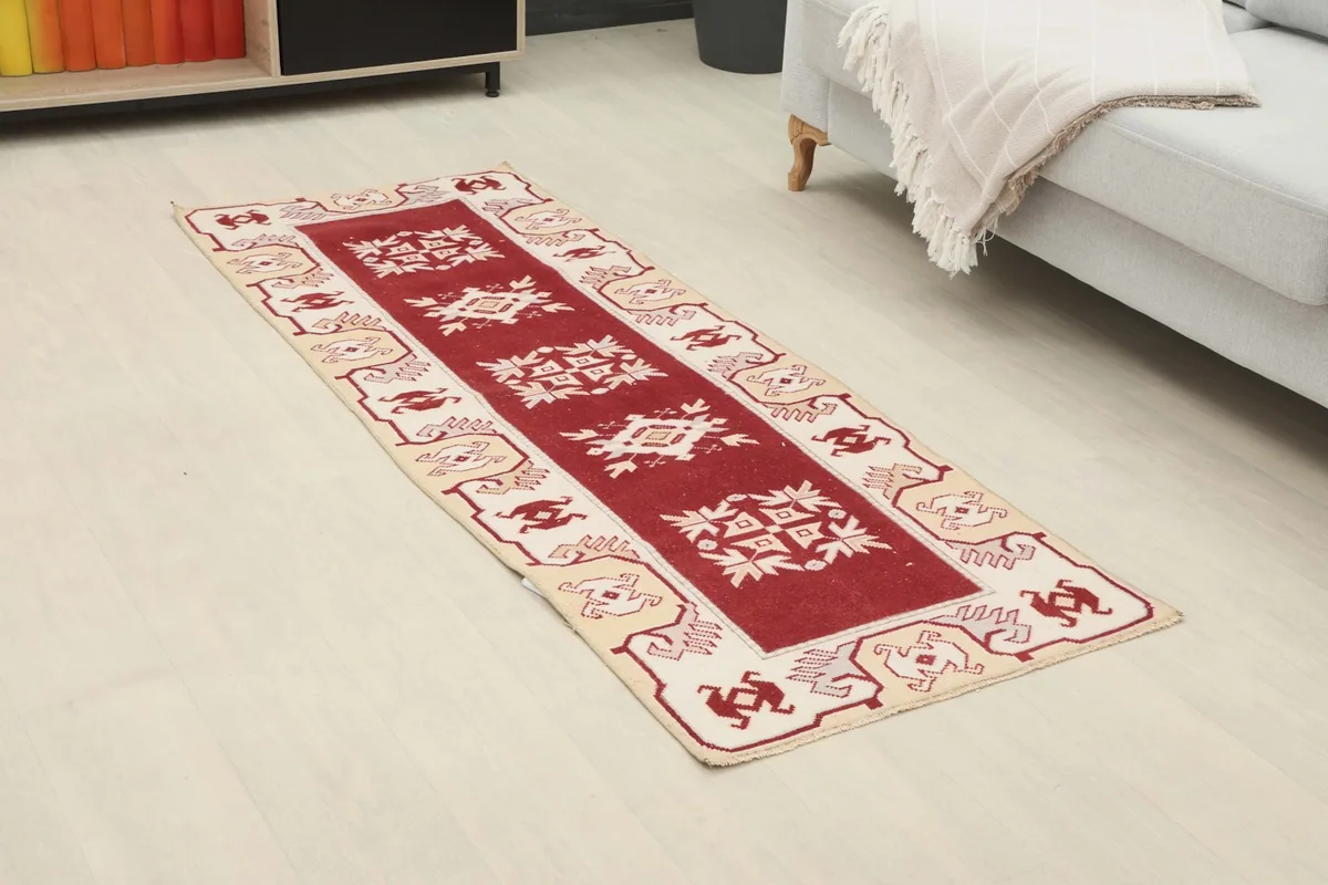 Angled view of the red and ivory runner in a room, showcasing its length and design.