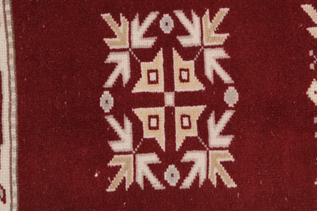 Detailed close-up of a central geometric motif on the red field.