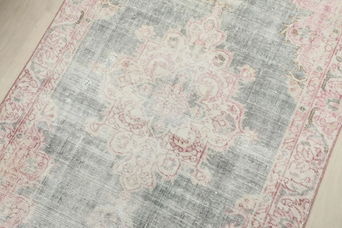 Close-up of the central medallion and floral motifs on the vintage gray and rose rug