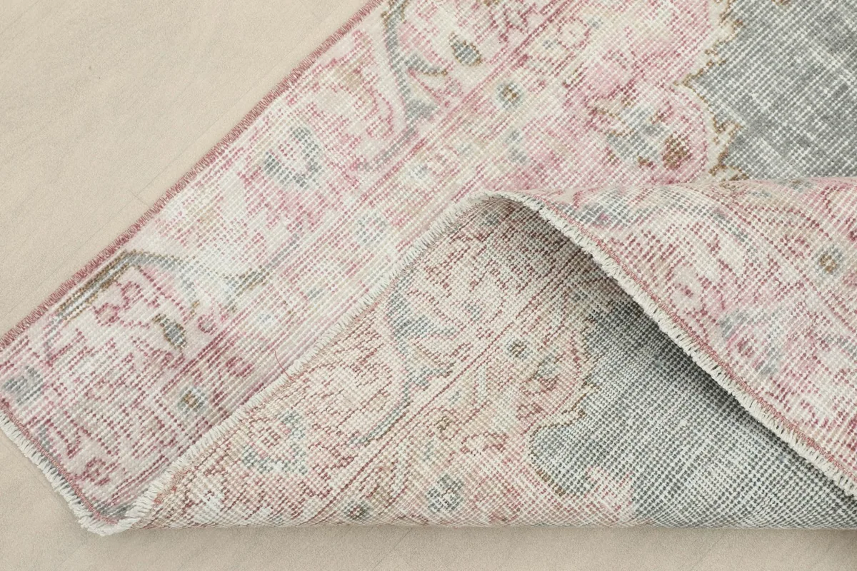 Corner of the rug folded back, revealing the cotton foundation and hand-knotted construction