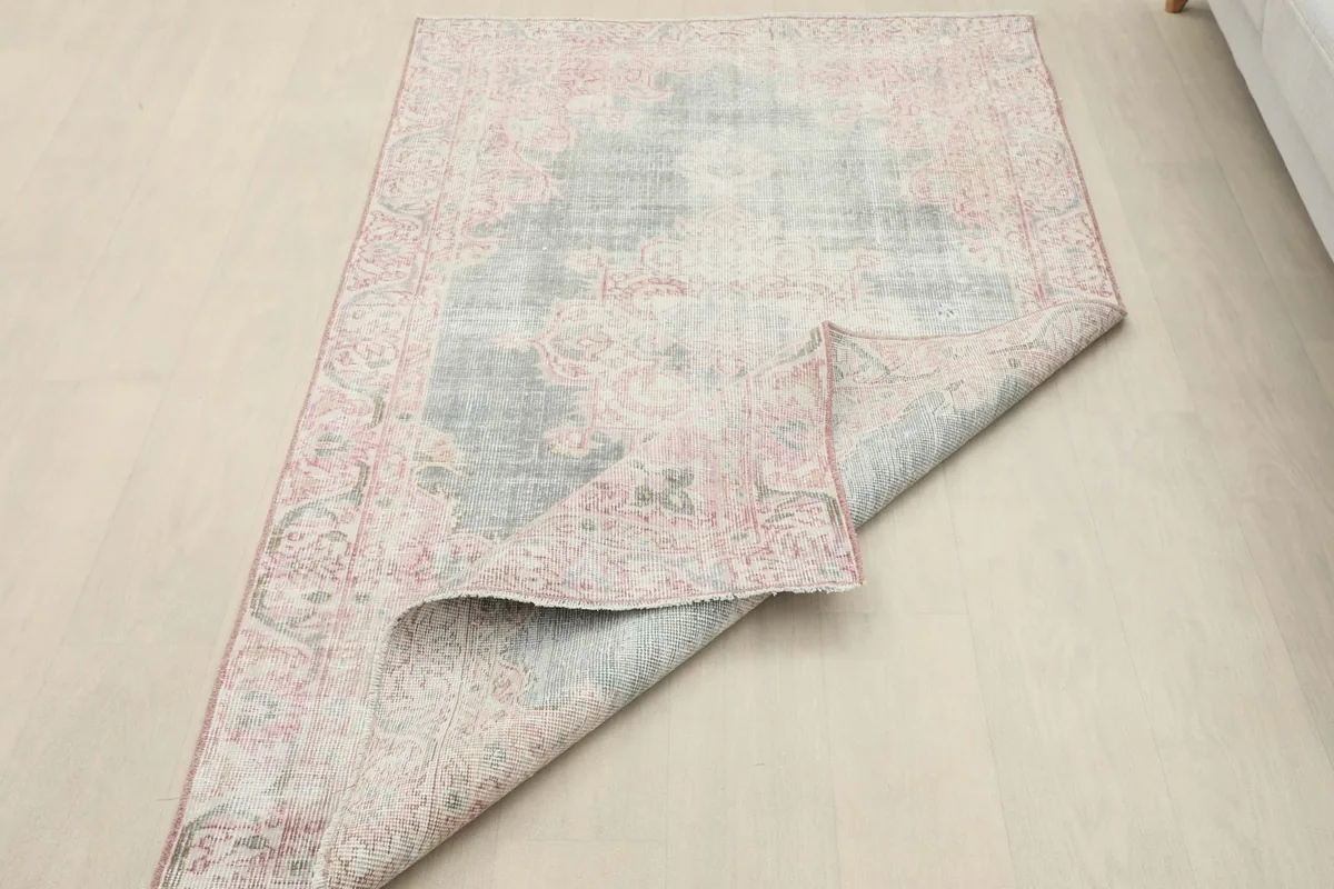Vintage rug partially folded, showcasing its flexibility and the reverse side of the foundation