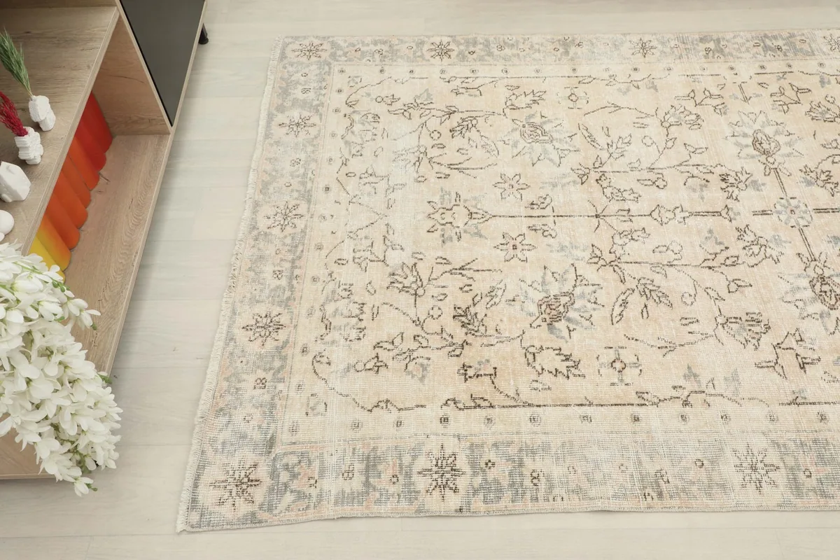Overhead angled shot showing the rug's motifs and the interplay of beige and charcoal colors.
