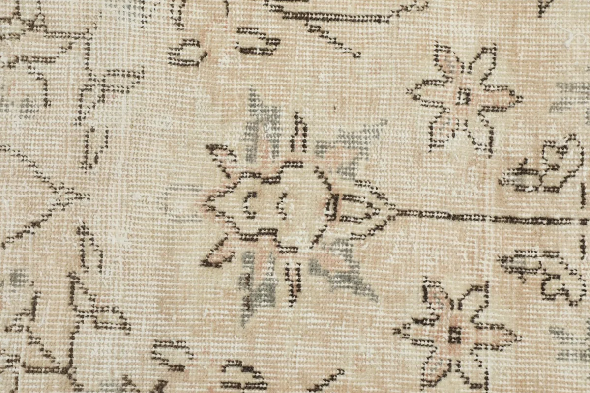 Extreme close-up of the hand-knotted floral motifs on the rug, showing slight wear and texture.