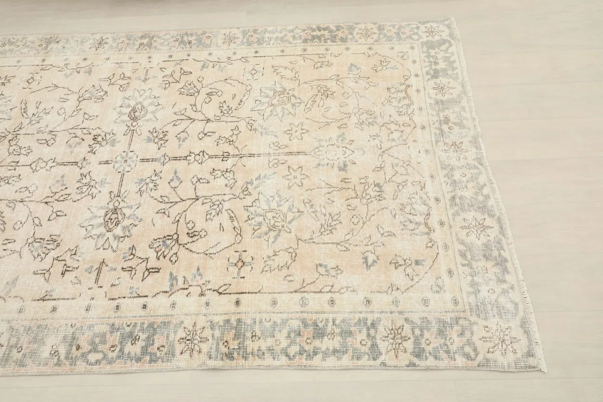 Close-up angled view of the rug's charcoal and gray border with subtle floral motifs.