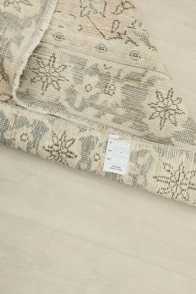 Close-up of the back of the rug with a label, showing the cotton foundation and hand-knotting.