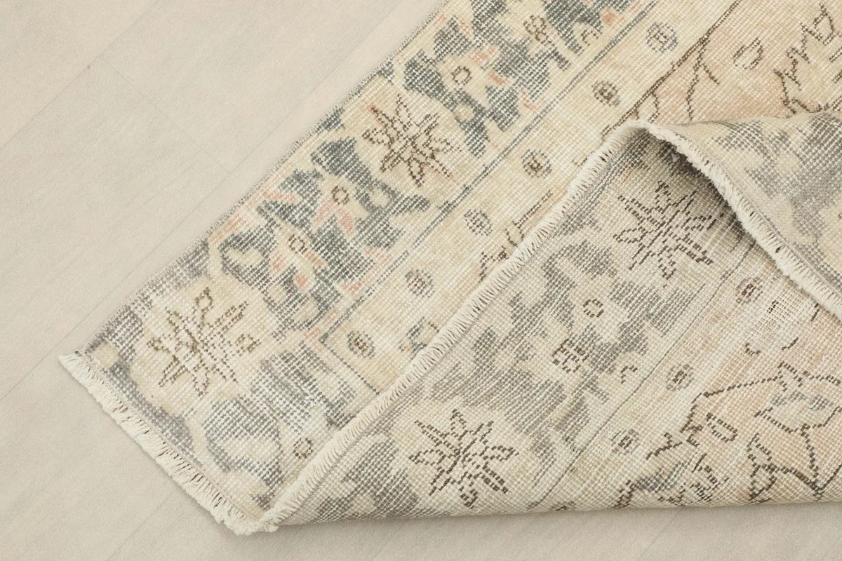 Corner of the rug folded back, revealing the reverse side and knotting detail.