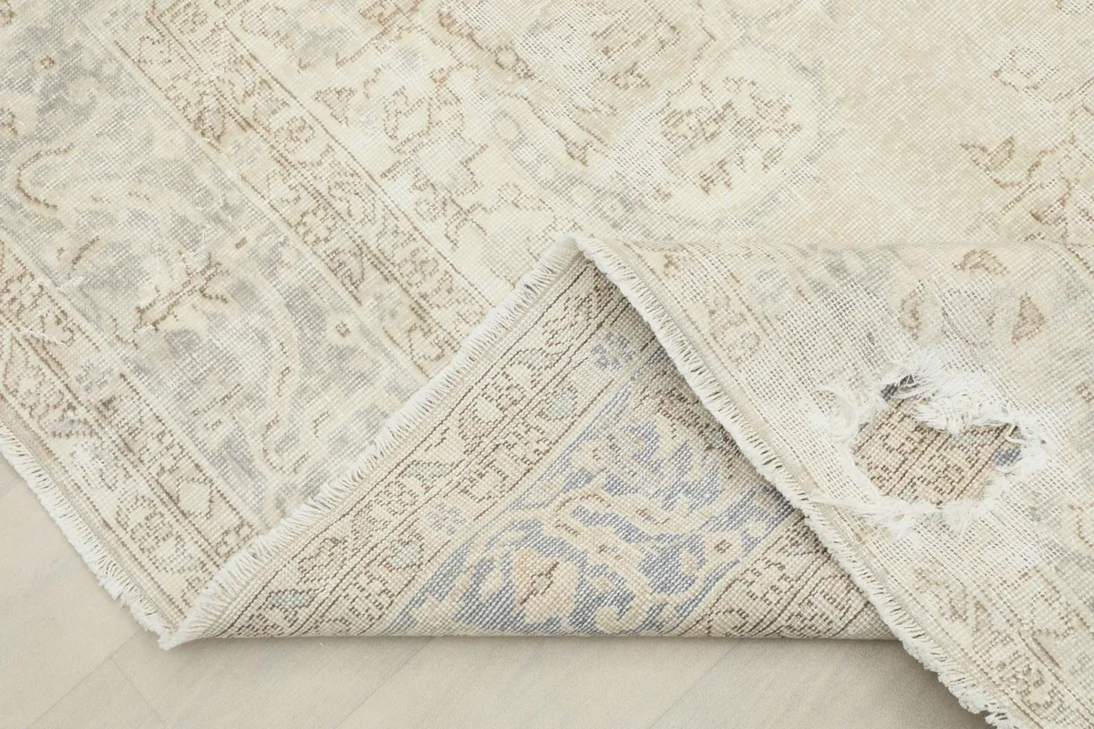 View of a corner folded back, revealing the cotton foundation and reverse side of the rug