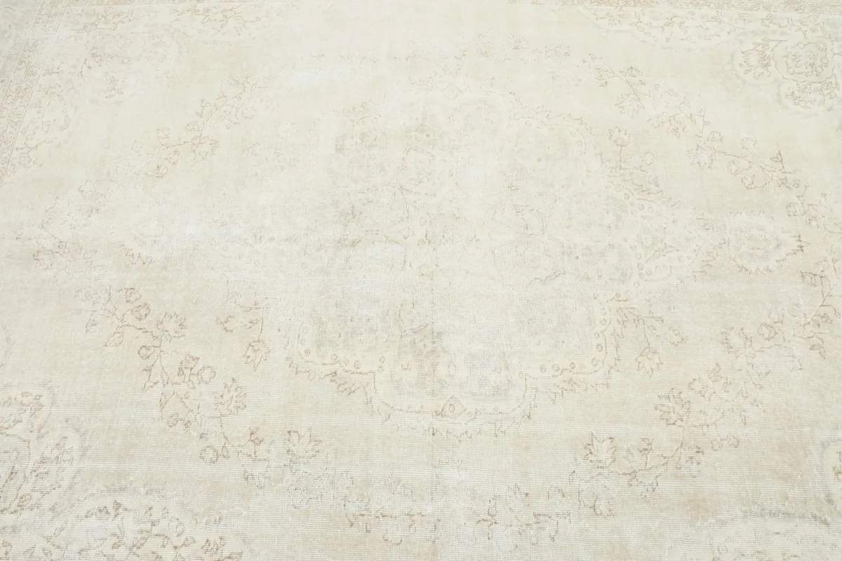 Close overhead view of the center of the rug, detailing the faded ivory and beige motifs