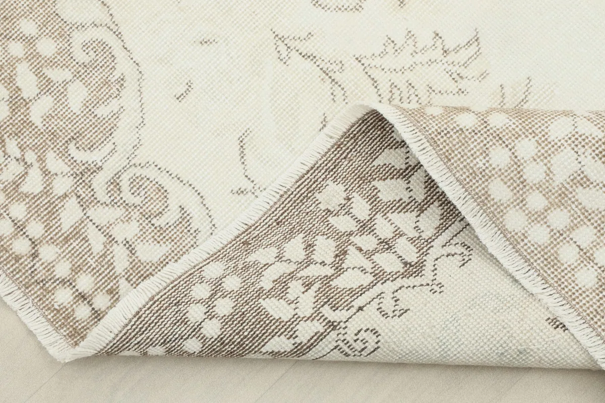 View of the rug folded back, showing the cotton foundation and the reverse side of the hand-knotted construction.