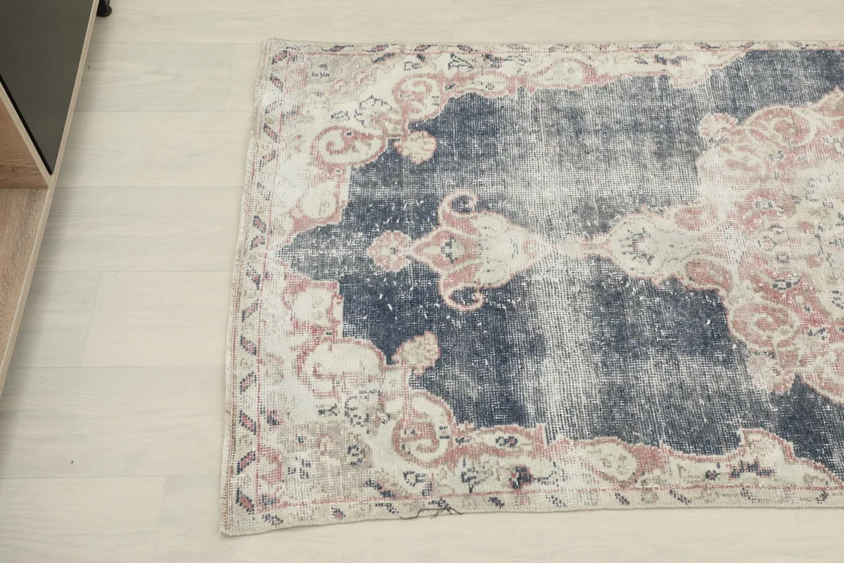 Angled view highlighting the distressed navy field and the cream and rose border details