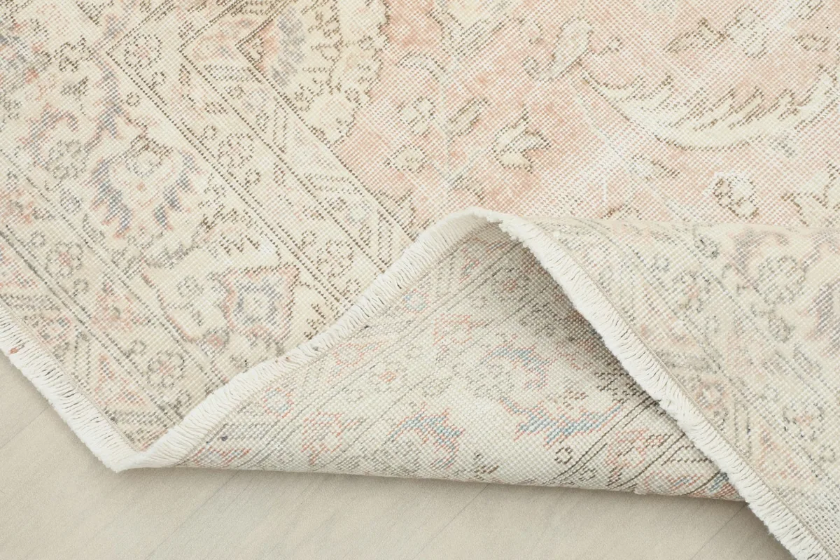 Corner of the rug folded back to show the cotton foundation and reverse side of the knotting