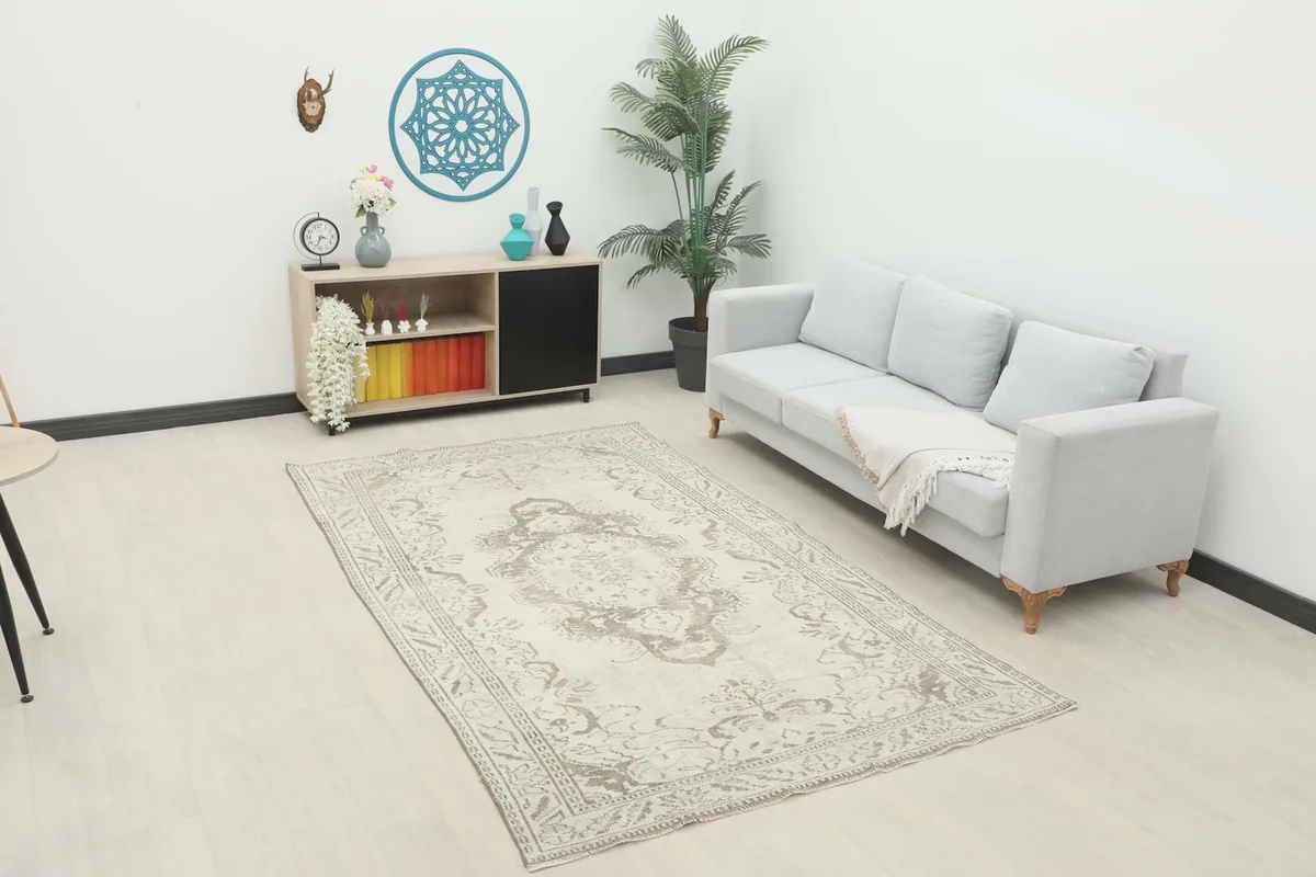 Ivory and tan vintage rug placed in a modern living room setting with a light gray sofa