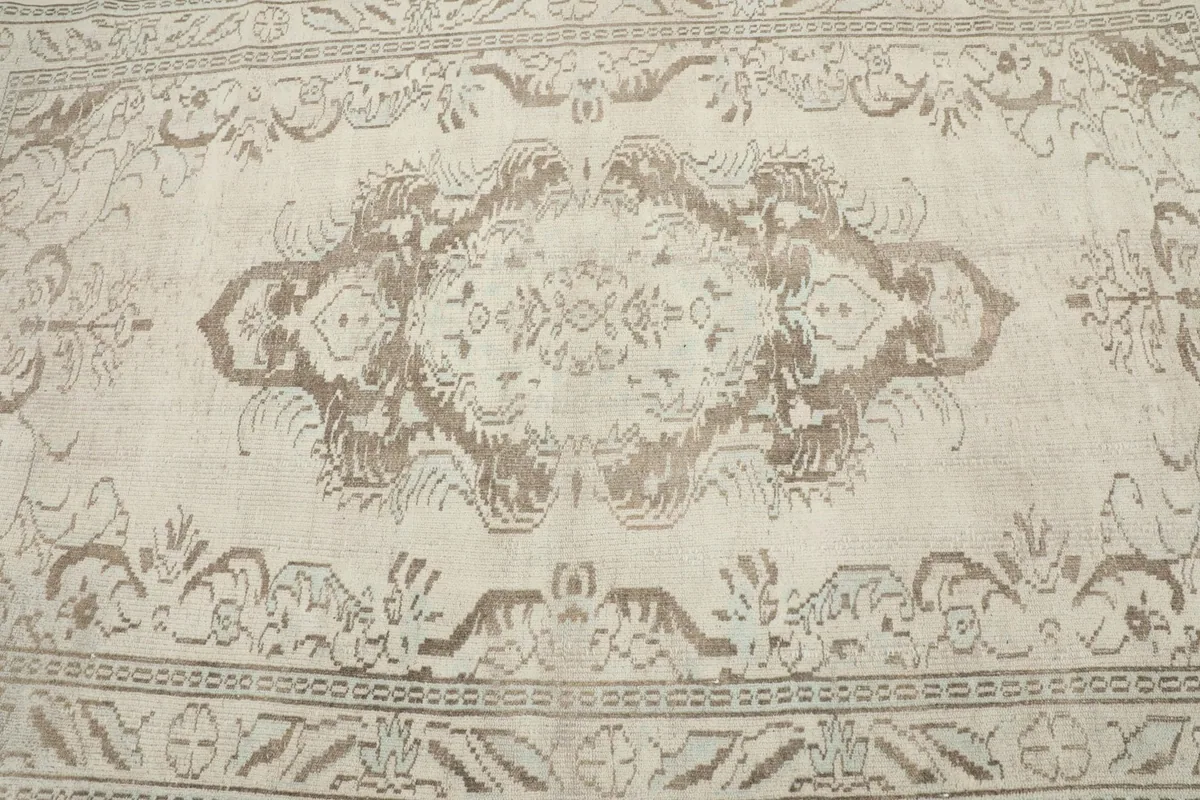 Detailed view of the central medallion motif in tan on the ivory field of the rug